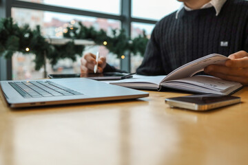 A professional workspace with a person organizing tasks using a notebook, tablet, and laptop on a...