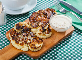 Grilled cauliflower on wooden cutting board