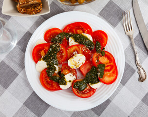 Traditional dish of Italian cuisine caprese salad with fresh tomatoes and mozzarella cheese at plate