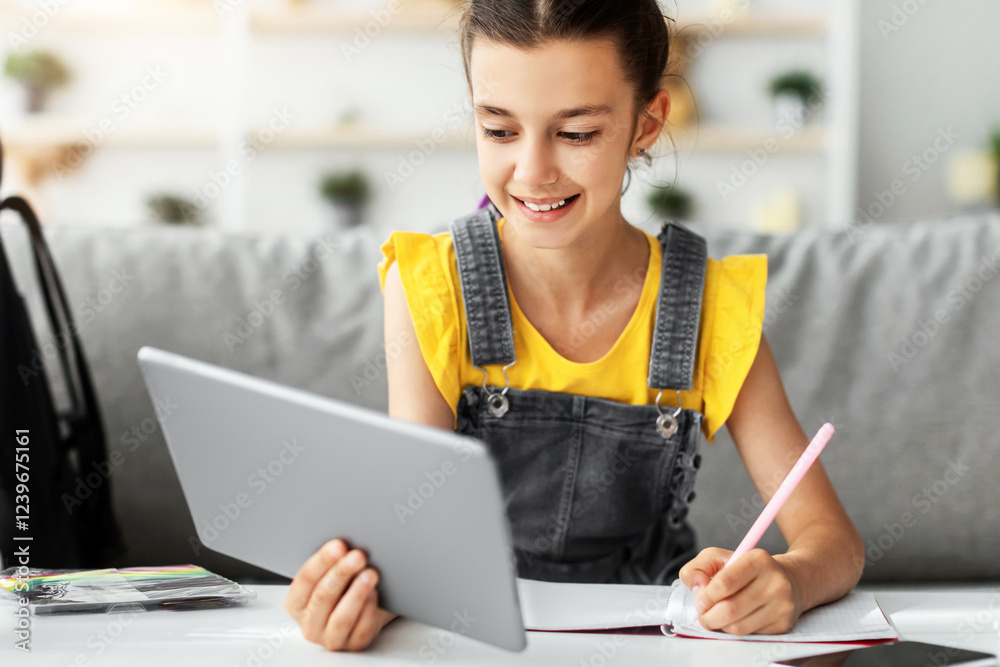 Poster portrait of smiling junior school kid girl holding digital tablet studying online during virtual cla
