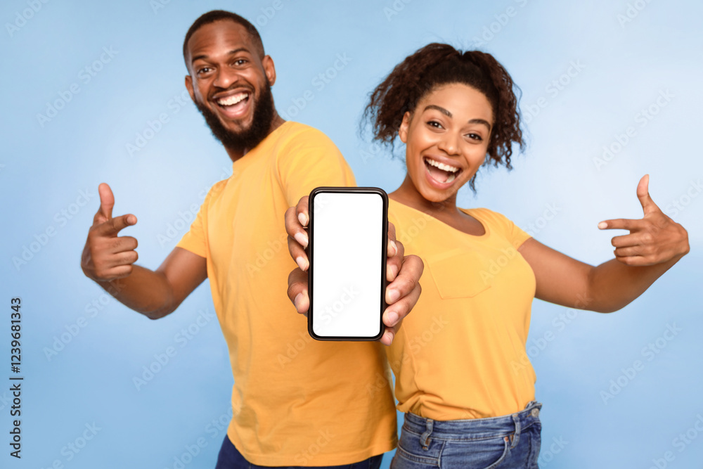 Poster mobile application ad. excited african american couple pointing at cellphone with blank screen, reco