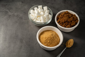 Different type of sugar, light brown, dark brown and white sugar cubes in bowls. 