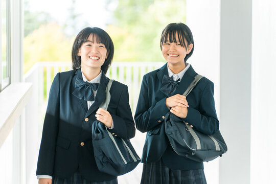 笑顔で校舎を歩く仲良しの女子学生（登校・下校・通学）
