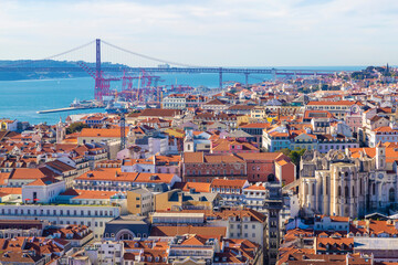 Skyline of Baixa, Chiado, Bairro Alto and Alcantara neighborhoods in Lisbon, Portugal, with April 25 Bridge in the background over the Tagus River