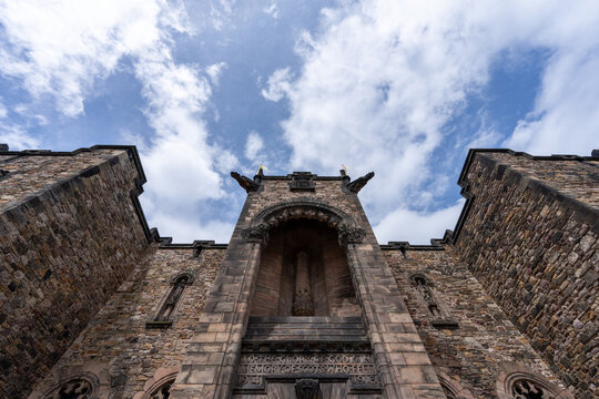 A majestic stone structure, possibly a church or castle, stands tall against a partly cloudy sky, its weathered stonework hinting at history.