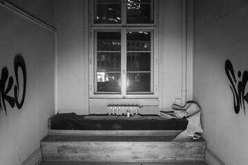 Night view of an abandoned building's room with graffiti and a window showing city lights.