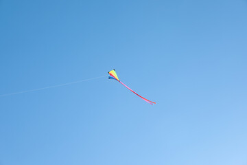 One colorful kite flying in blue sky