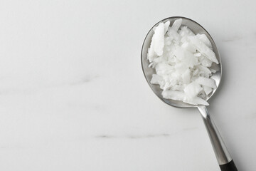 Soy wax in spoon on white marble table, top view. Space for text