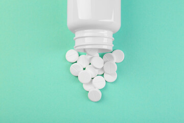 Bottle of antibiotic pills on turquoise background, top view