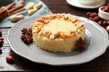 Delicious semolina halva with almond flakes and spices on wooden table, closeup