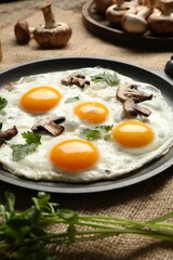 Tasty fried eggs with mushrooms and parsley served on table, closeup