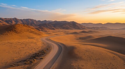Naklejka premium Aerial Desert Road at Sunset Golden Light Bathes Rocky Terrain
