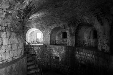A descending stone staircase leads into a dimly lit, historic underground passage with arched...