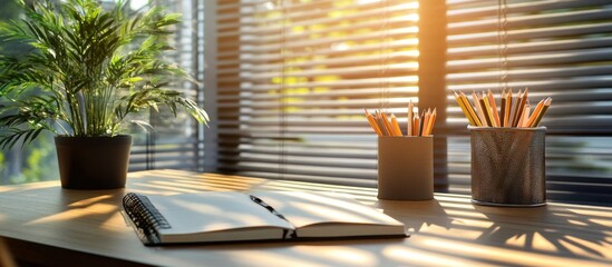 Fototapeta premium Sunny Workspace: Notebook, Pencils, and Plant