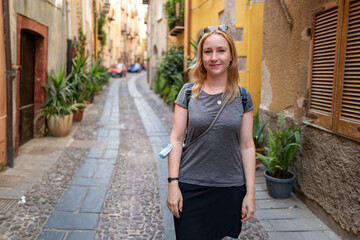 Smiling woman takes a relaxing stroll along a charming cobblestone street in a historic European...