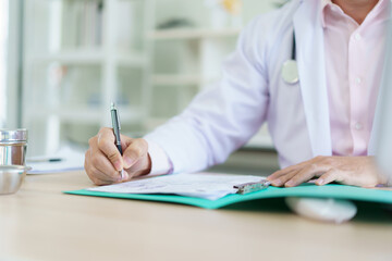 Asian doctor is working on a documents and papers report in the office in hospital.