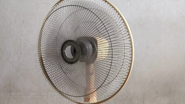 The front of electric table fan is spinning and forth, decreasing heating and increasing cooling on concrete background.