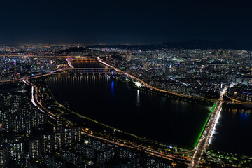 Fototapeta premium A captivating night view of Seoul's cityscape, showcasing its bridges, river, and illuminated roads, creating a vibrant scene.