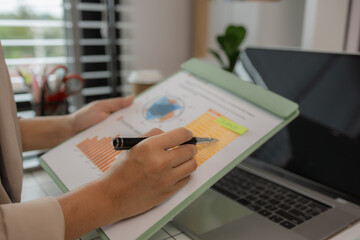 a businesswoman is sitting in her private office working on her desk with many documents to check, a lot of marketing documents were reviewed by the team leader