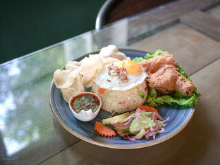 Fried rice served with fried chicken, egg, chilli sauce, lettuce and etc. 