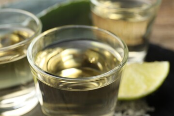Mexican tequila shots and slice of lime on table, closeup