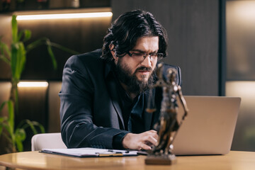 A business-minded male lawyer works late at night in a modern office with a laptop, brainstorming...