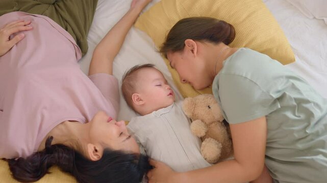 Asian lesbian couple lovingly caring for and raising their baby boy at home. 