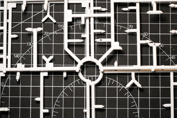 White plastic model kit runner frame on black cutting mat. Remaining plastic runner frame after cutting model kit parts. Wallpapers Backgrounds. Abstract Texture. White and black colours