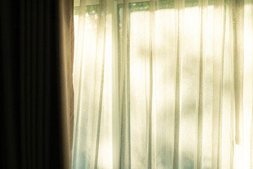 Soft light on curtains window. There was morning light through the window in room, looking at the view of the mountains and trees as the sun rose.