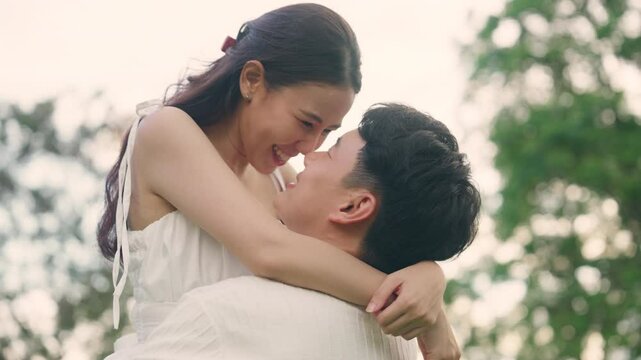Young adult asia people happy lover flirt at public nature park falling in love desire kiss hug beloved care trust. Sweet asian lovers tender face to face man woman smile relax warm time date day.