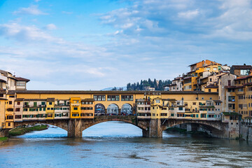 Obraz premium The Ponte Vecchio, Old Bridge, a Medieval stone closed-spandrel segmental arch bridge over the Arno River, with shops built along it; as jewelers, art dealers, souvenir sellers. Florence, Italy, 2019