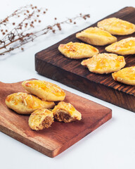Indonesian nastar snack with pineapple jam filling. Soft, golden pastries are arranged on two wooden boards, showcasing delicious treats in a warm kitchen atmosphere