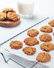 Cookies are cooling on a wire rack next to a glass of milk in a warm kitchen, inviting a delightful snack time