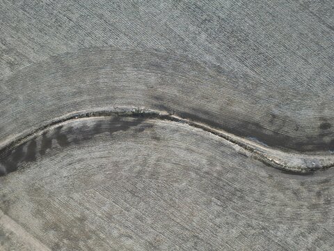 Vertical aerial view of a drainage ditch winding through a freshly ploughed field - Vue a&eacute;rienne verticale d'un foss&eacute; de drainage qui serpente au milieu d'un champ fraichement labour&eacute;