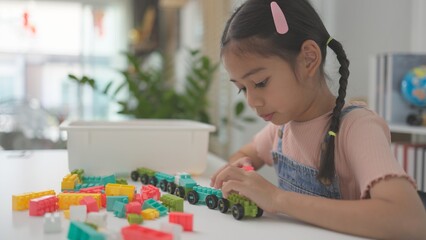 Child playing with colorful toy blocks. Kids play. Little girls building a tower of block toys. Educational game for babies and toddlers. Children build a toy house