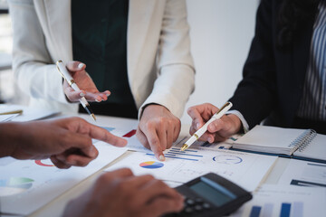 Business team analyzing financial charts and graphs using calculator during a meeting