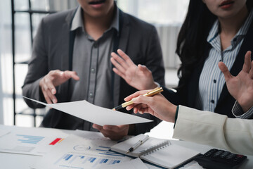 Business people discussing and reviewing documents and graphs pointing with pen during meeting