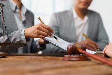 Lawyers reviewing contract with client in office with gavel and scales of justice