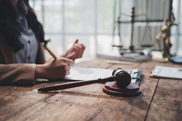 Obraz premium Lawyer signing legal document with gavel and justice scale on wooden table