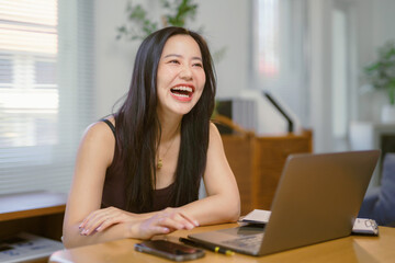 Young Asian Freelancer Woman is Laughing While Working From Home