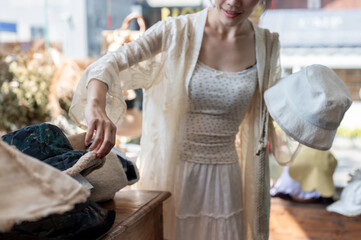 A close-up of an Asian woman carefully selecting items in a hat shop, enjoying her shopping spree.