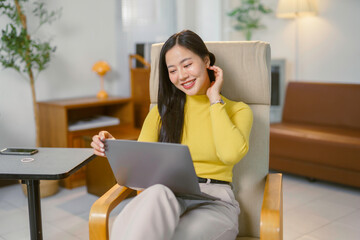 Young Asian businesswoman using laptop and smiling while working from home