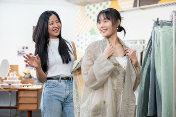 A friendly Asian female store employee is helping a customer select an item, giving a compliment.