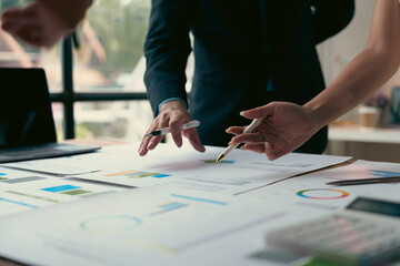 Business people analyzing financial charts and graphs using pens in the office
