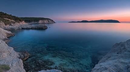 Serene sunset over calm turquoise sea and rocky coast.