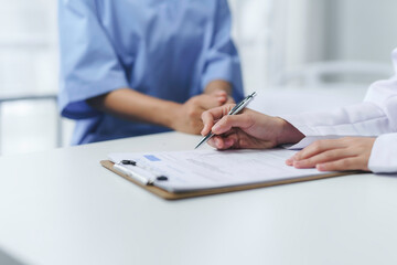 Doctor writing medical records while interviewing patient in hospital room