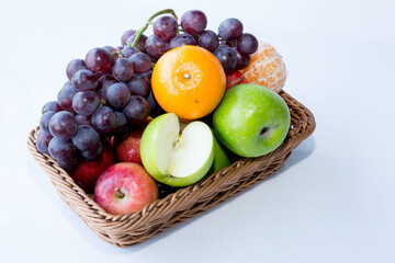 assorted fresh fruits apple,orange,grapes,  in a square basket on white background, with copy space.
