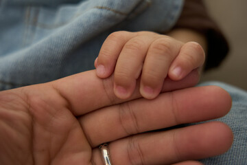 Fototapeta premium someone holding a baby ' s hand with a ring on it