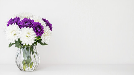Fototapeta premium A vibrant bouquet of purple and white flowers in a clear vase, set against a minimalistic white background.