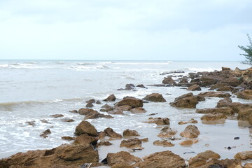 Fototapeta premium Rocky Beach Shoreline with Waves and Cloudy Sky